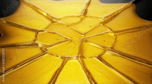 A close-up shot of a broken yellow glass surface with cracked lines spreading from the center.