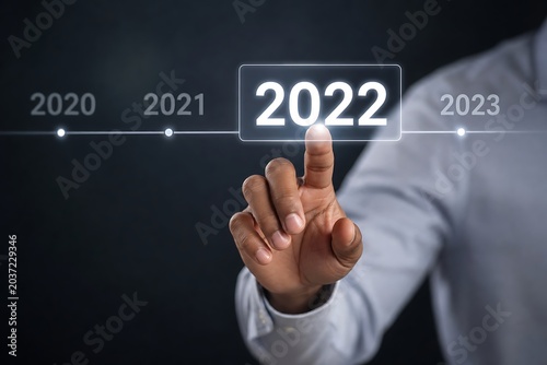 Hand touches the year 2022 on a digital timeline, signifying the selection of the current year or future planning.