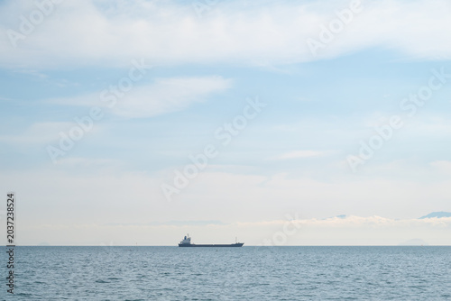 Cuadro en lienzo Lone Cargo Ship on Calm Seto Inland Sea with Soft Blue Sky and Distant Mountains