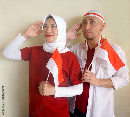 Two Asian Man And Woman Showing Salute And Respect Gesture While Holding National Flag. Sports, Supporter And Independence Day Celebration Concept