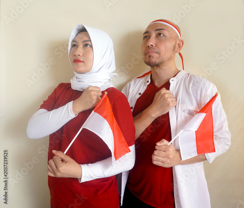 Asian Couple Put Hand On Chest Showing Salute or Respect Gesture While Listening National Anthem. Sports, Supporter And Independence Day Celebration Concept 