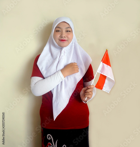 Young Girl Put Hand On Chest Showing Respect While Holding Indonesian Flag. Education, Football Fan and Independence Day Concept