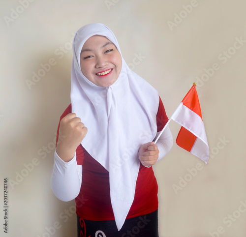 Cheerful Young Girl Clenched Fist Showing Victory At Camera While Holding Little Flag. Football Fans, Sports And Indonesia Independence Day Celebration