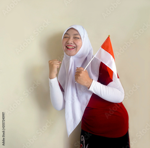 Young Girl Clenched Fist Showing Excitement And Support For Her Football Team While Holding National Flag. Victory, Fan And Indonesian Independence Day Celebration Concept