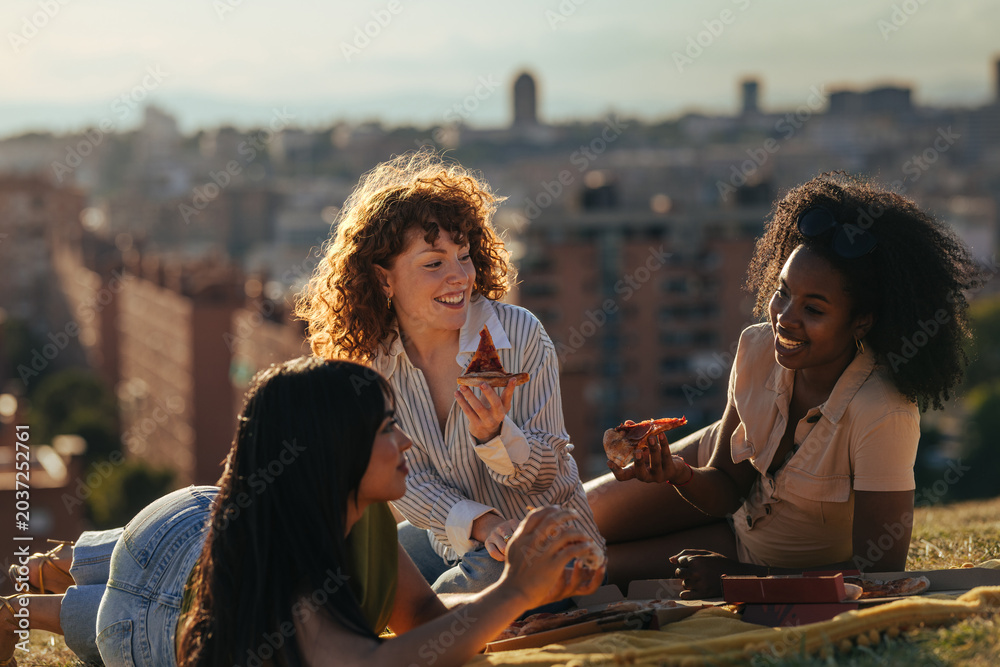 Obraz premium Diverse women friends sharing pizza picnic