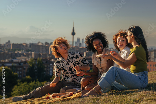 Friends having outdoor pizza picnic overlooking Madrid city