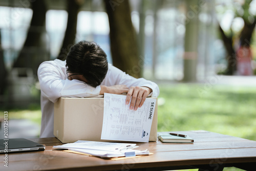 Tableau sur toile Unemployed professional leaning on a box with a resume in hand, expressing job loss, emotional stress, career uncertainty, and the challenges of finding new employment