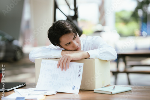 Foto Unemployed professional leaning on a box with a resume in hand, expressing job loss, emotional stress, career uncertainty, and the challenges of finding new employment