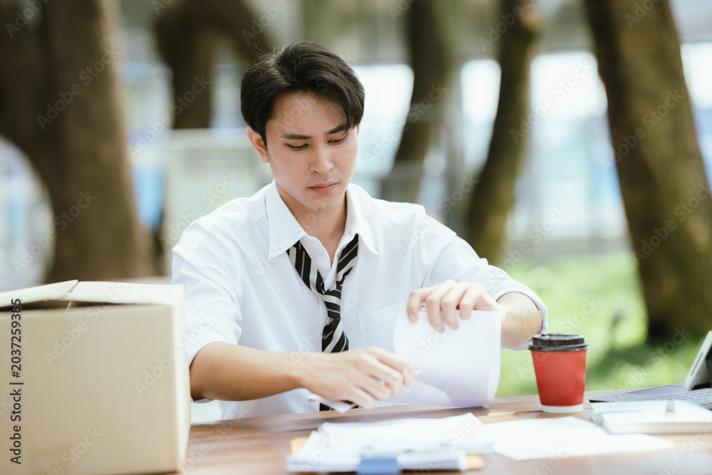 Fototapeta premium Frustrated unemployed professional tearing documents after job loss, expressing stress, career uncertainty, financial hardship, and the emotional impact of unemployment.