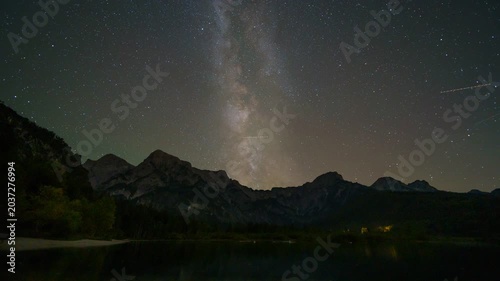 Time lapse in the night of sky with stars, milky way, satellites over mountains and lake 
