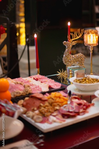 Charcuterie board loaded with sliced salami, cured meats, walnuts, dried figs, and apricots, served with tongs at an elegant buffet.