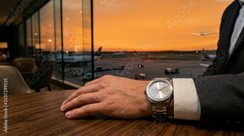 Luxury Business Travel: Man's Watch in VIP Airport Lounge at Sunset