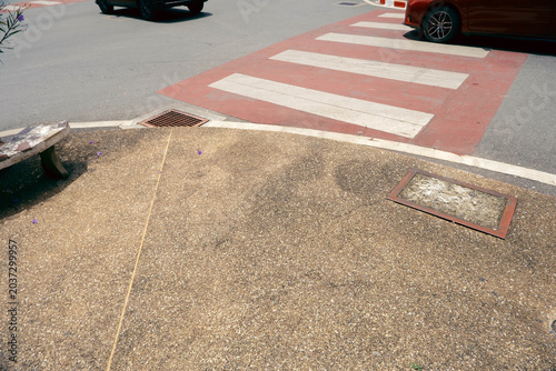 Red and white zebra crossing next to a pedestrian sidewalk on a city street
