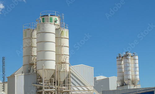 Fotografie Concrete mixing plant silos and storage tanks stand tall against a clear blue sk