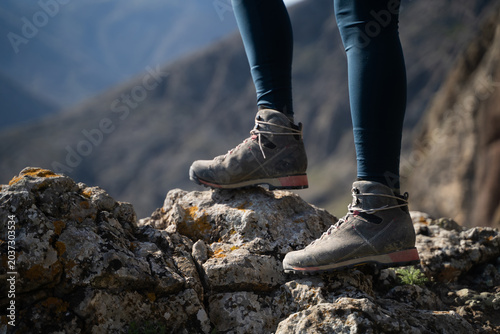 Close-up of female hiking boots on rocks during a mountain trekking adventure on a summer day.

