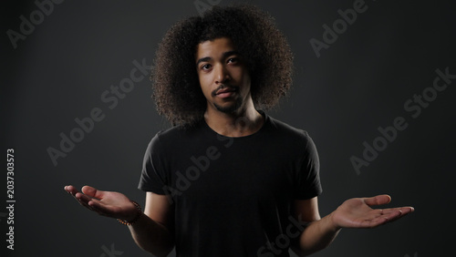 Foto Young man shrugging with open hands, showing confusion or searching for answers
