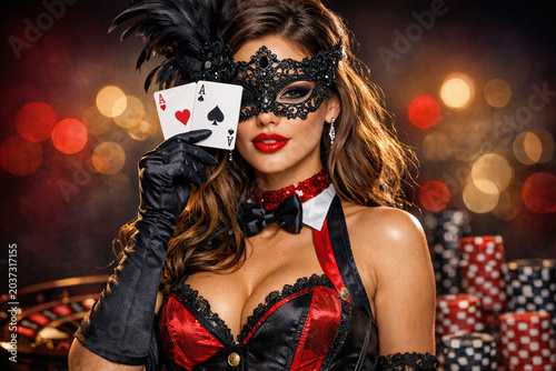 A woman dressed in a black and red masquerade outfit with a mask, holding up cards as if she's about to play poker.