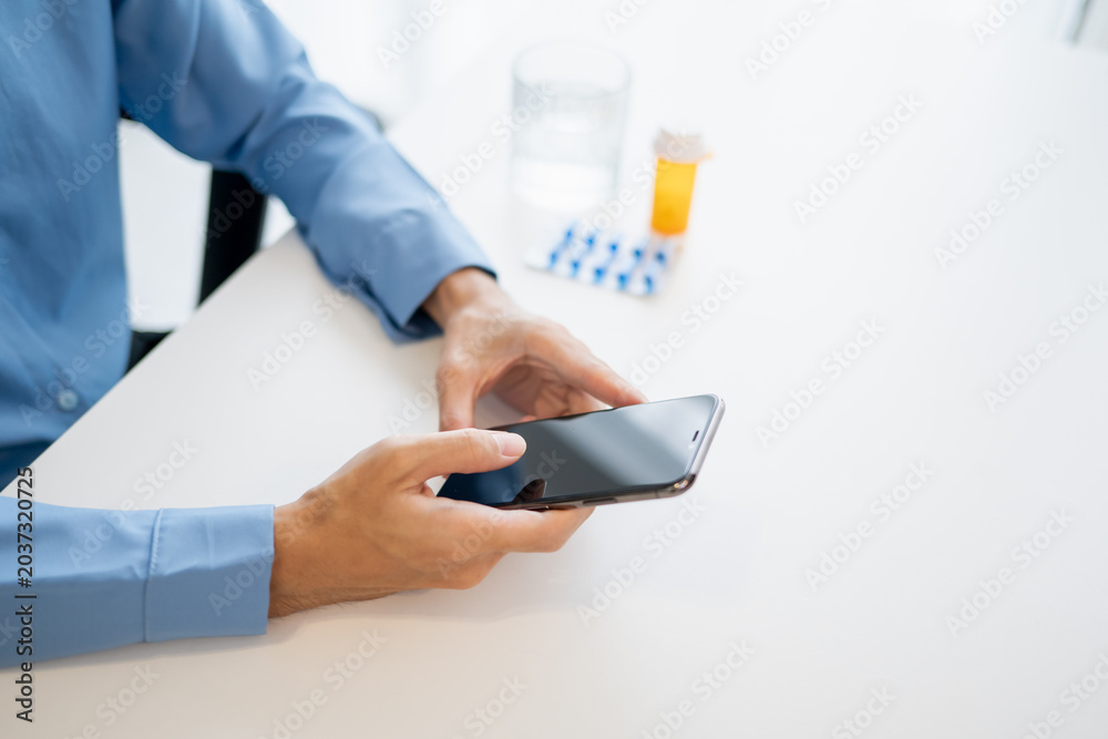 Fototapeta premium Man using mobile health app and AI technology for medication health tracking with pills and vitamins.