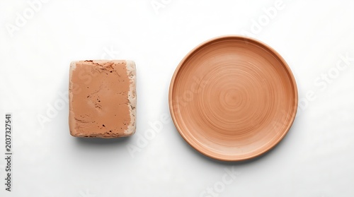 Top-down view of a clay plate and a block of clay on a white surface.
