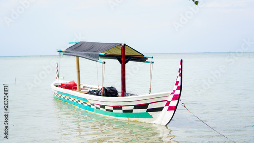 Photos A scenic coastal view featuring a traditional boat with decorative patterns rest