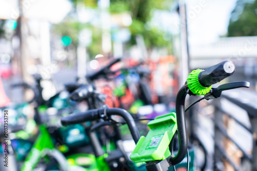 Focused view of green Anywheel bike handlebars, featuring an intricate green textured handle, phone holder with a QR code for mobile app unlocking, and a brake lever.