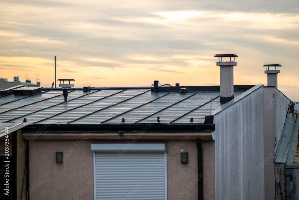 Fototapeta premium Modern house rooftop with chimneys at sunset