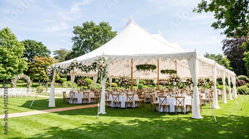 Elegant outdoor wedding setup with a large white tent and beautifully arranged tables.