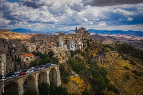 Aerial drone view of town Petralia Soprana, Sicily, Italy. An avenue of trees leading to the hilltop in the Madonie Mountains. August 2024