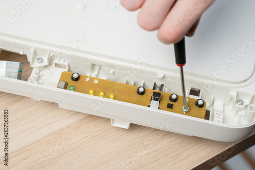 Close-Up Of Hand Using Screwdriver To Repair Electronic Circuit Board Inside All in one Printer