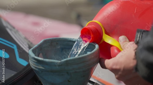 Filling a sports car with racing fuel from a canister