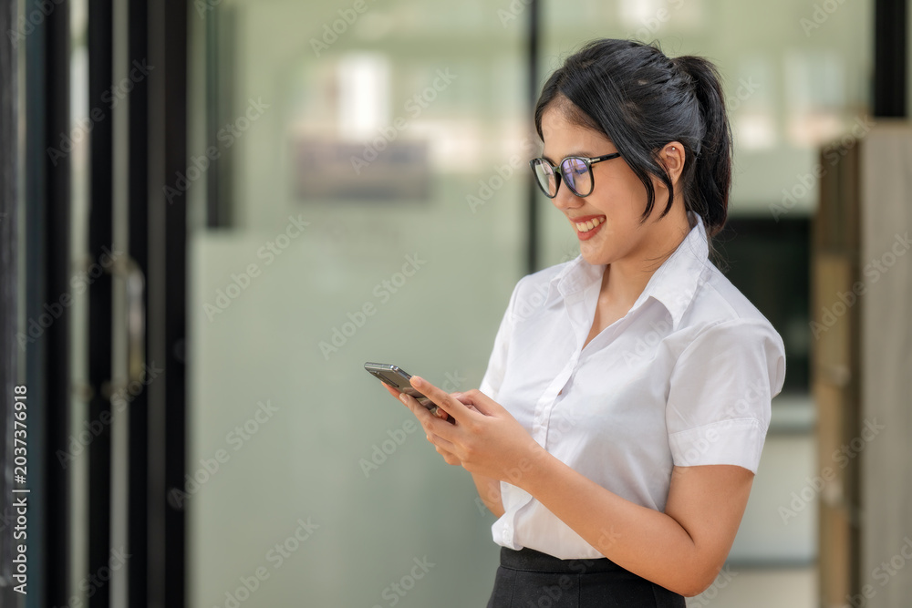 Φωτογραφία Happy young Asian woman with glasses smiling while texting on smartphone