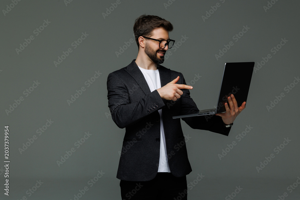 Sticker Young business man pointed on laptop screen on gray background