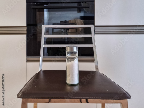Glass salt shaker filled with white salt on a modern kitchen bar stool