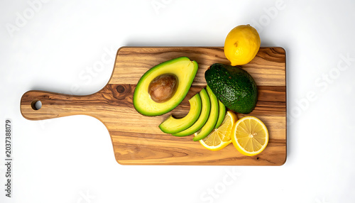 Fresh avocado cut and sliced with lemon on a wooden cutting board, healthy food ingredients for cooking