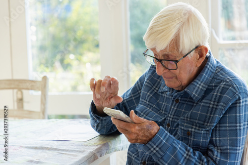 elderly man sitting at table using smart phone