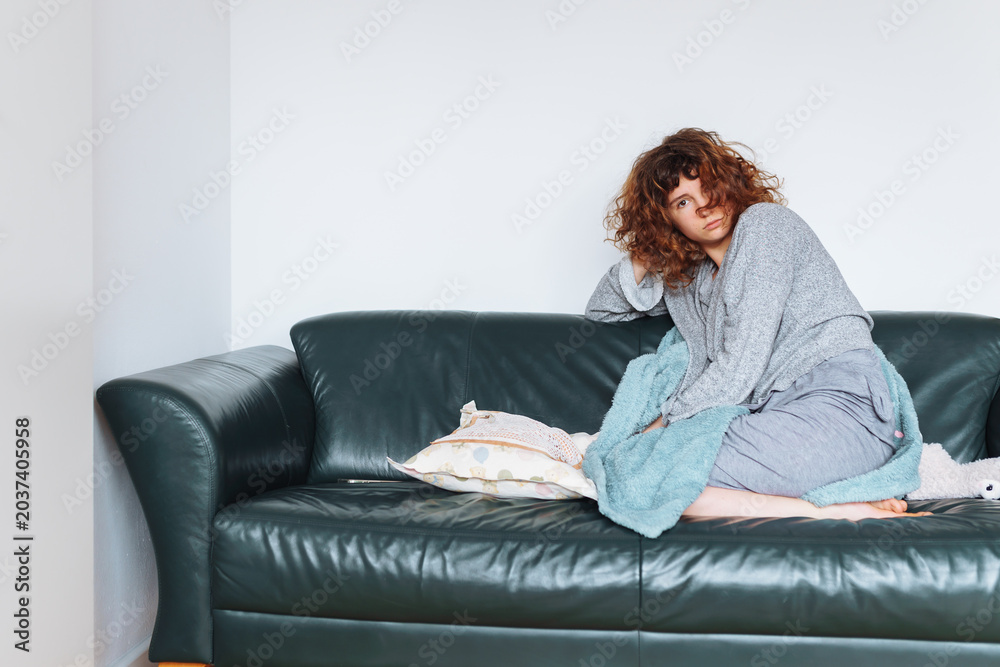 Obraz premium young red-haired woman relaxing on leather sofa