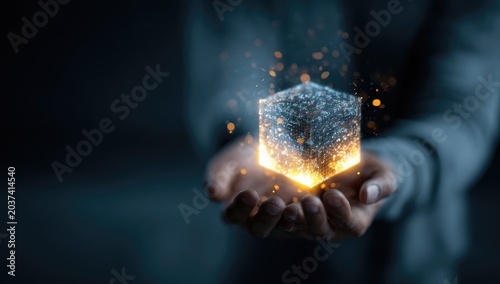 Hands cradle glowing, textured cube emitting light particles against dark background