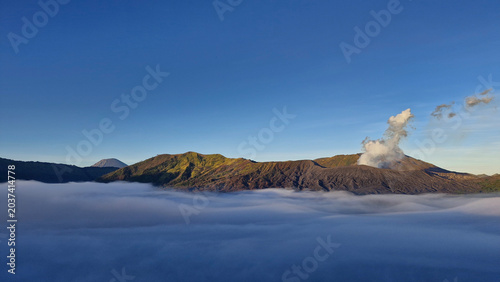 Obraz na płótnie Mountain ridges surrounding the Bromo caldera emerging above a blanket of clouds in East Java, Indonesia