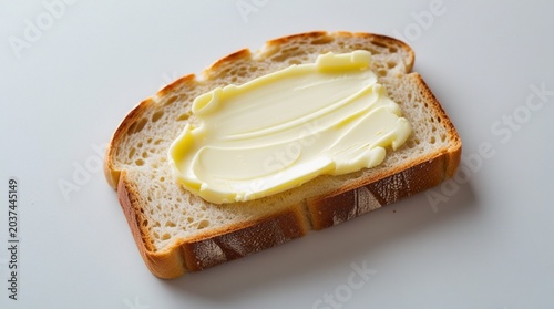 Slice of bread with creamy butter spread, simple breakfast food isolated on clean white background