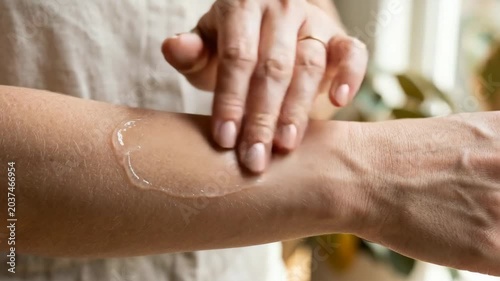 Applying Aloe Vera Gel: Close-up of a woman's hand applying clear aloe vera gel to her arm, showcasing skin hydration and natural wellness.