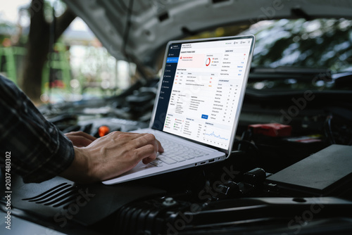 Foto Technician using a laptop to diagnose engine performance under an open hood, analyzing vehicle data and troubleshooting automotive issues with digital diagnostic software