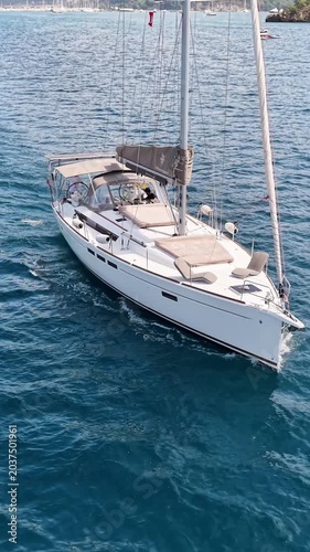 Sleek white sailboat glides across sparkling blue ocean waters on a sunny day