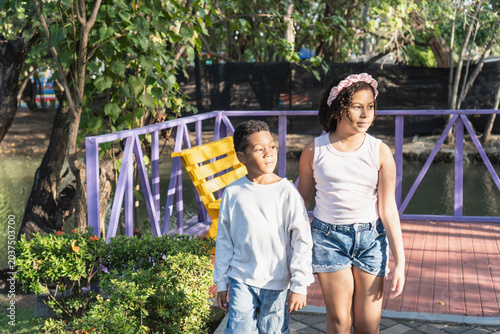 Young siblings standing outdoors in a park