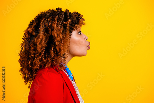 Φωτογραφία Stylish woman in red jacket puckering lips in profile against bright yellow back