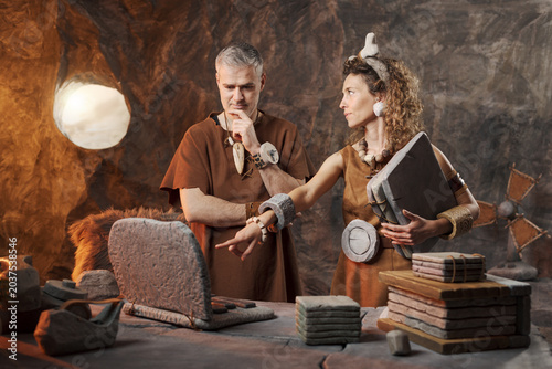 Canvastavla Caveman and Cavewoman Collaborating on Stone Laptop – Prehistoric Office Teamwor