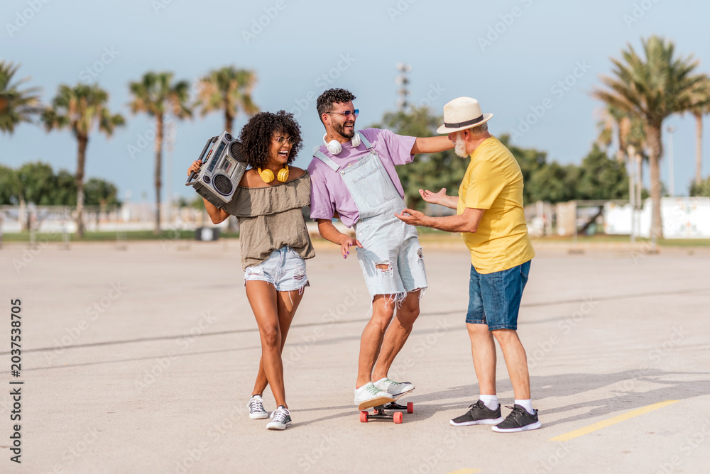 Obraz premium Multigenerational family having fun outdoors with music and skateboard
