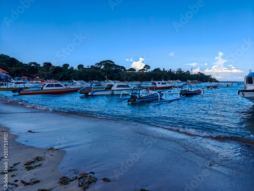 Tableau sur toile Fleet of speedboats and traditional outriggers moored in the calm waters of Pada