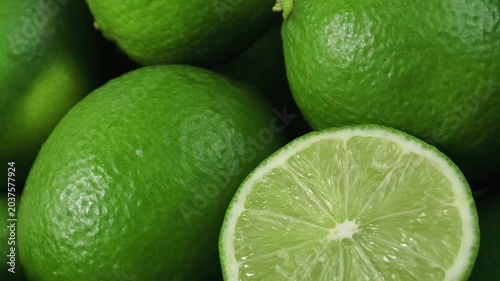 A pile of whole limes with multiple cut halves