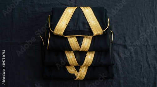 Elegant Saudi cloaks folded neatly with intricate gold embroidery, showcasing traditional