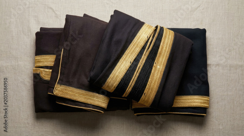 Elegant Saudi cloaks folded neatly with intricate golden embroidery, showcasing traditional